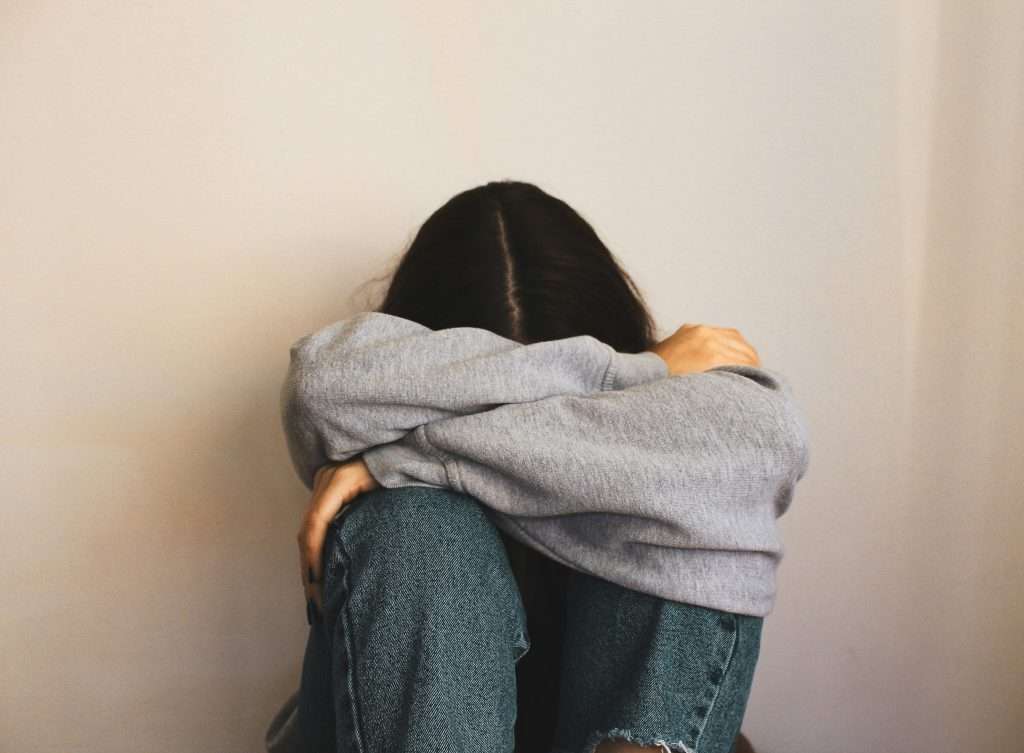 a person sitting with their hands on their knees